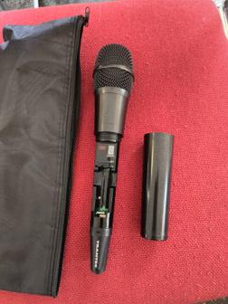 The hand-held radio mic, with the unscrewed battery cover